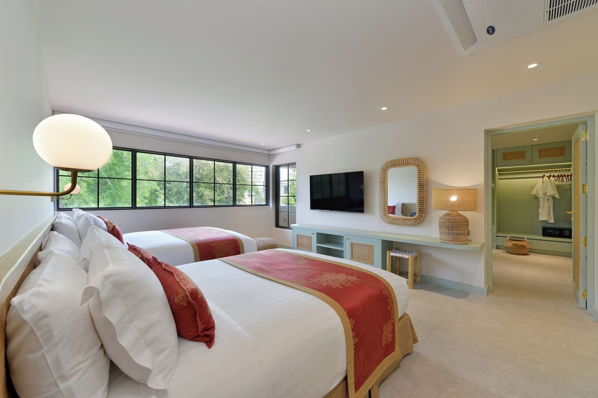 Een hotelkamer met twee bedden, een televisie, een spiegel en een kledingkast.