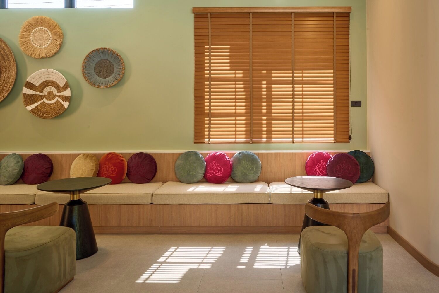 A seating area with a wooden bench, colorful cushions, and woven wall art.
