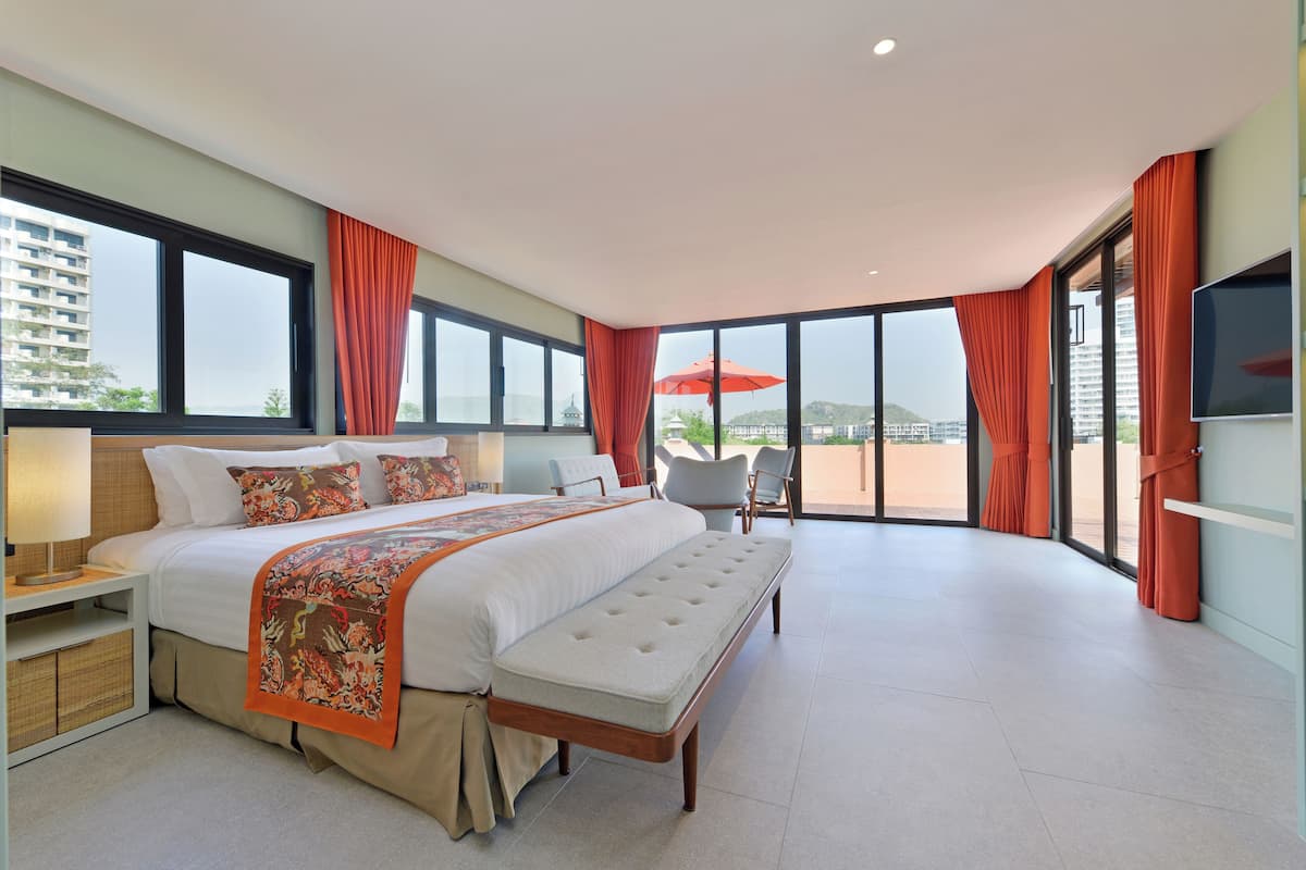Een moderne hotelkamer met een groot bed, een bankje, een televisie en een balkon met uitzicht op de stad.