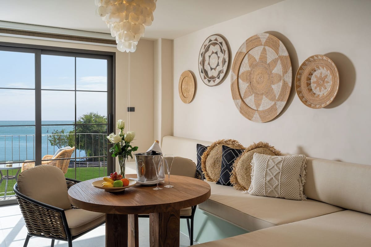 Een moderne woonkamer met een ronde houten tafel, een bank met geweven kussens en decoratieve borden aan de muur.