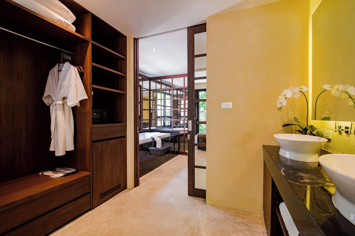 Un baño moderno con tocador de madera, un espejo grande y vistas al cuarto contiguo.