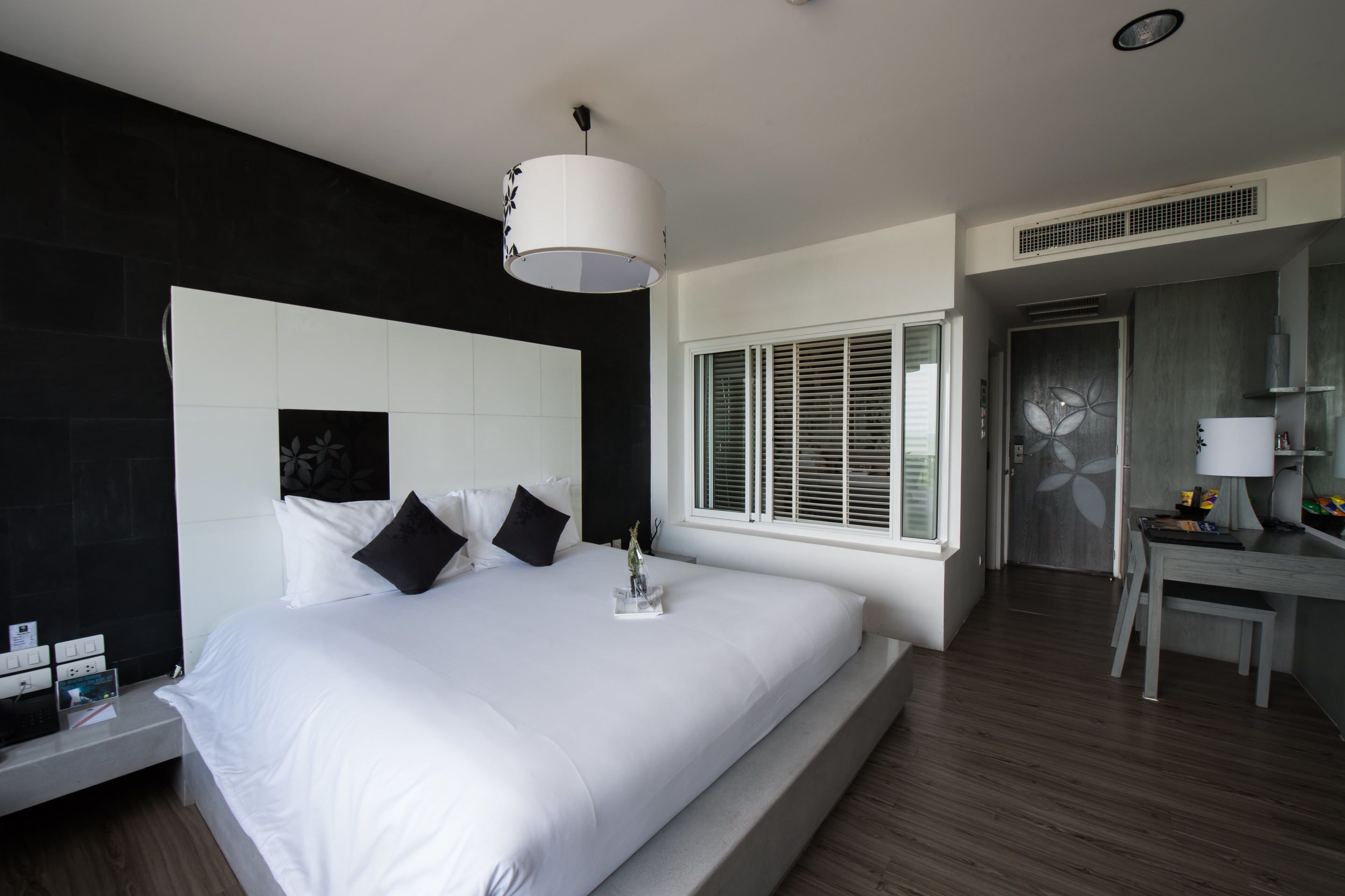 Una habitación de hotel moderna con una cama grande, un escritorio y una ventana con persianas.