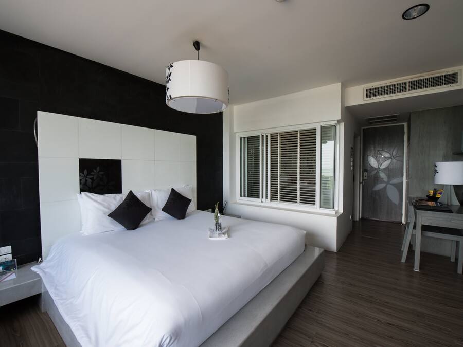 Una habitación de hotel moderna con una cama grande, un escritorio y una ventana con persianas.