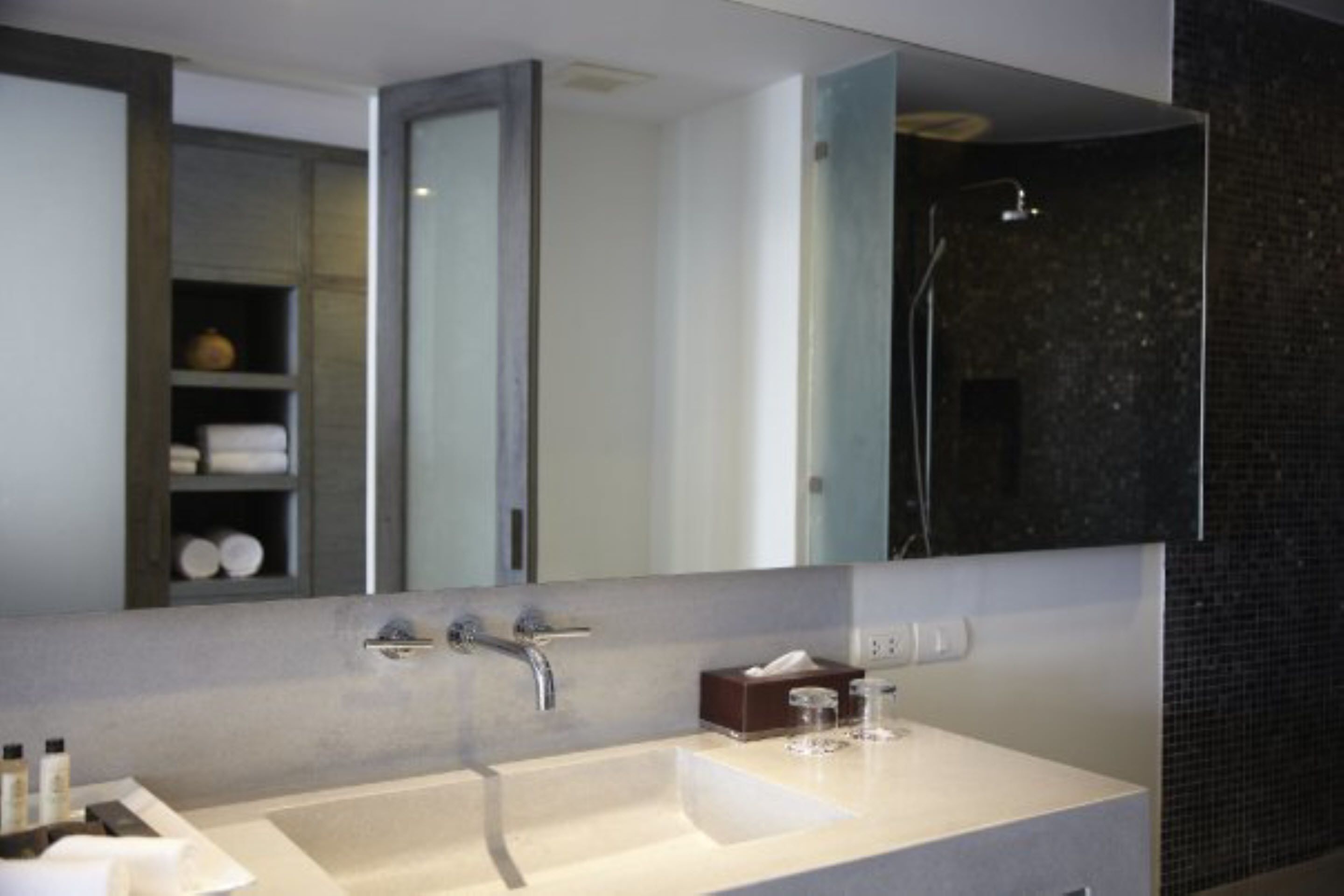 Een moderne badkamer met een grote spiegel, een witte wastafel en een douchehoek.