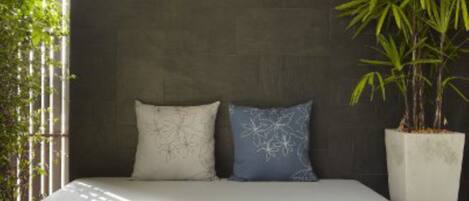 A modern bedroom with a dark wall, a bed with white and blue pillows, and a potted plant.