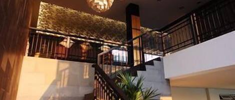 A staircase with a railing, leading to a landing with a patterned wall and hanging light fixtures.