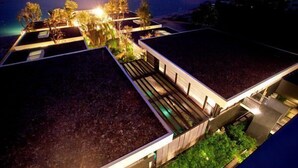 Un edificio moderno con techo plano, varias terrazas y una zona de piscina.