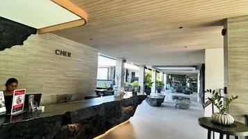 Un área de recepción con mostrador de piedra, techo de madera y un cartel que dice 'CHER'.