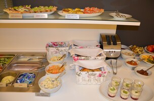 Buffet com diversas opções de comida, incluindo sanduíches, patês e saladas.