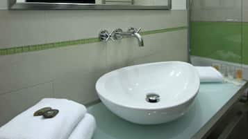 Un baño con lavamanos blanco, un espejo y una ducha.