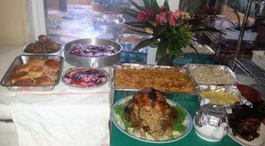 Una mesa de buffet con diversos platos, como un pollo asado, productos horneados y guarniciones variadas.