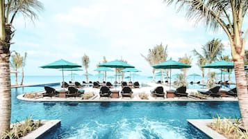 Una piscina al aire libre, sombrillas, sillones reclinables de piscina