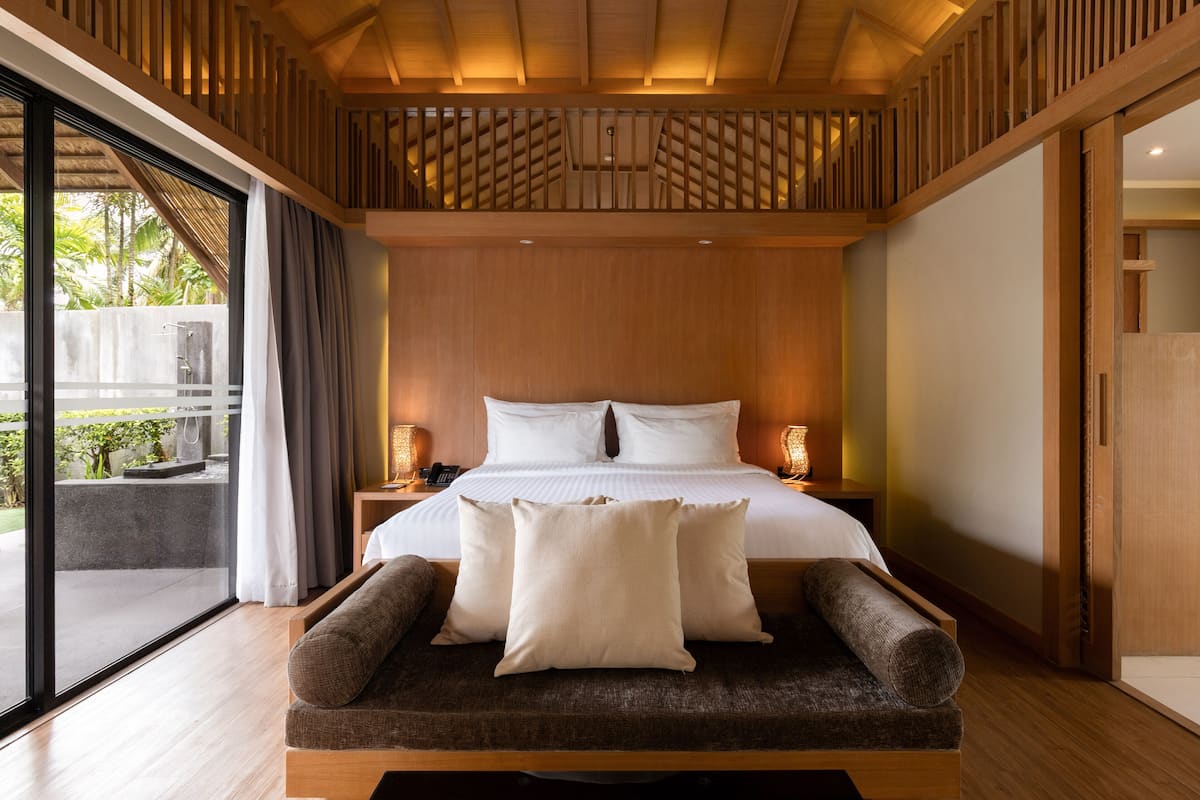 Un dormitorio moderno con una cama grande, cabecera de madera y vistas al exterior.