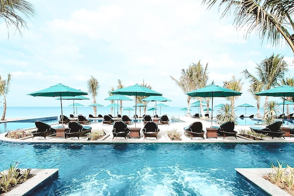 Een buitenzwembad, parasols bij het zwembad en ligstoelen