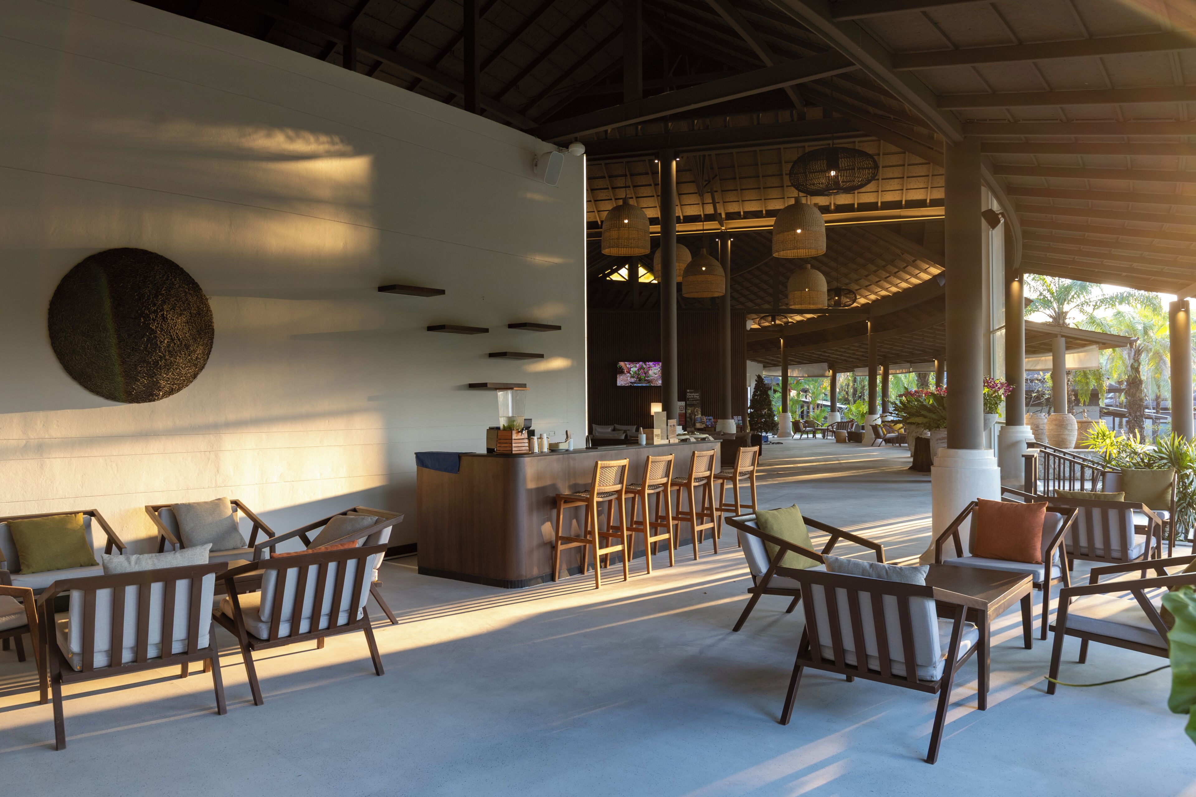 A spacious outdoor seating area with a bar, wicker furniture, and a large wall-mounted TV.