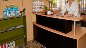 A reception desk with a clock, a plant, and a sign indicating 24-hour surveillance. - Sundale Motel (Southport)
