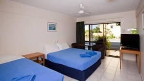 A hotel room with two beds, a TV, a small table, and a balcony with a view. - Sundale Motel (Southport)