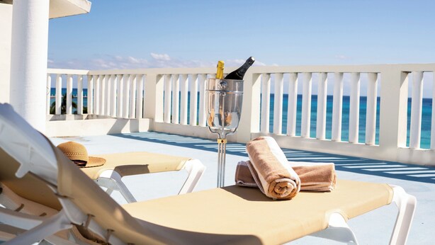 A balcony with white railings, a glass of champagne, and a sun lounger with a towel. - Posada Sian Kaan Playa del Carmen - Wellness Oriented Hotel (Playa del Carmen)