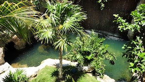 A serene garden with a water feature, lush greenery, and a rocky terrain. - Posada Sian Kaan Playa del Carmen - Wellness Oriented Hotel (Playa del Carmen)
