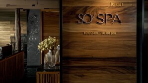 Zona de recepción con una pared de madera que muestra el nombre 'SO'SPA' y el horario de atención.