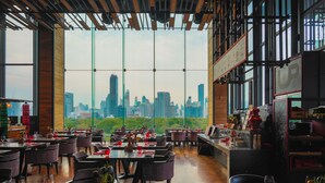 Un restaurante con vistas a un horizonte urbano, amplias ventanas y una decoración de diseño moderno.