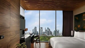 Una habitación de hotel moderna con vista al horizonte de la ciudad, una cama grande, un escritorio y una silla.