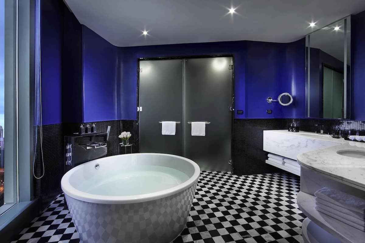 Une salle de bain moderne avec une baignoire sur pieds, un grand miroir et un carrelage à motifs géométriques.