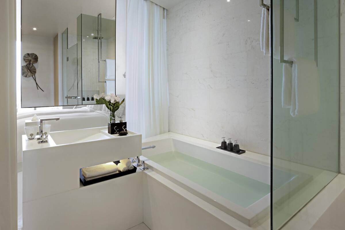 Une salle de bain moderne avec une douche à parois de verre, une baignoire blanche et un meuble-lavabo avec un miroir et un évier.