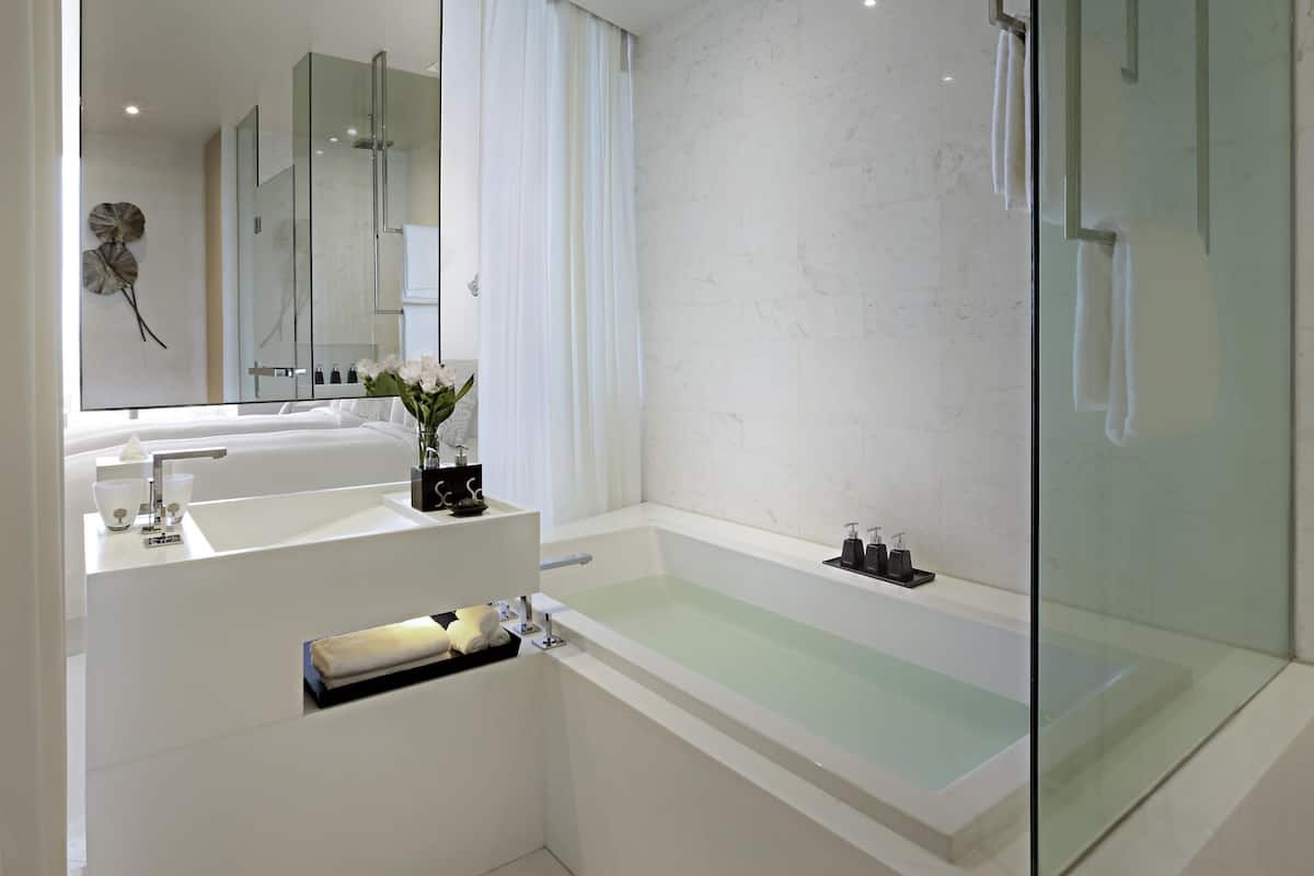 A modern bathroom with a glass shower enclosure, a white bathtub, and a vanity with a mirror and sink.