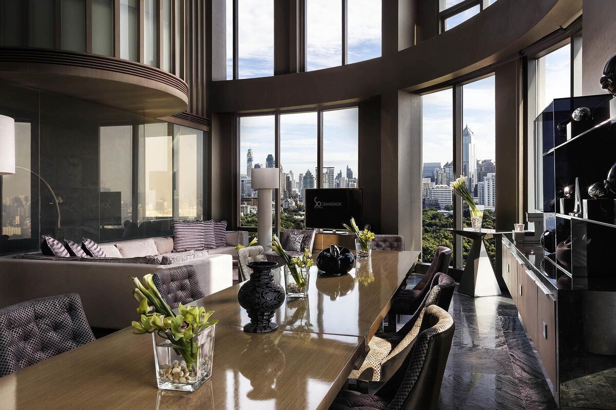 Una habitación de hotel moderna con un amplio comedor, asientos y vistas a la ciudad.