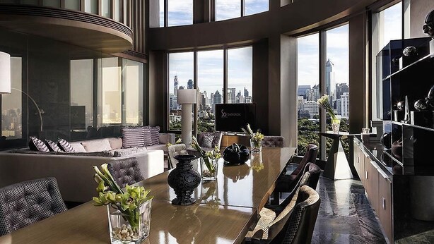 A modern interior with a dining area, seating, and a city view through large windows. - SO/ Bangkok (Bangkok)