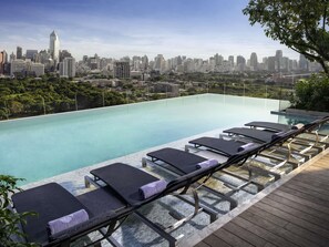 A rooftop infinity pool with lounge chairs, a city skyline view, and a wooden deck. - SO/ Bangkok (Bangkok)