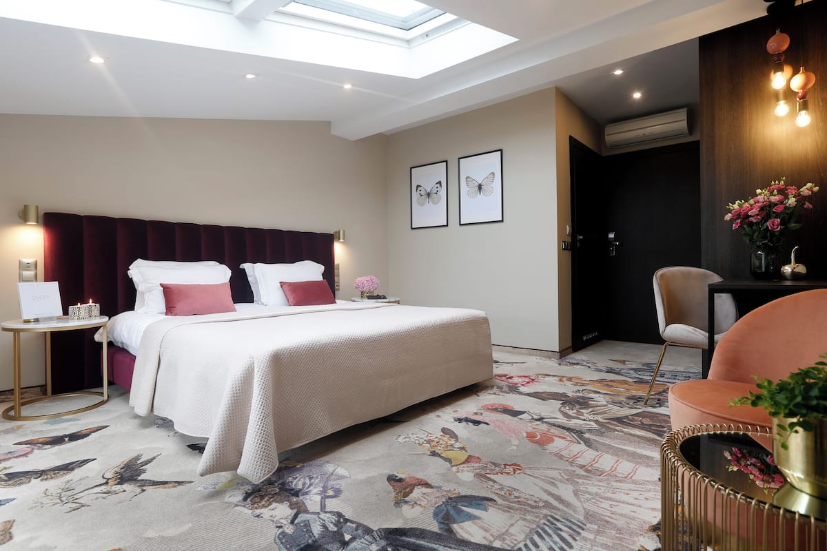 A modern hotel room with a large bed, a desk, a chair, and a skylight.