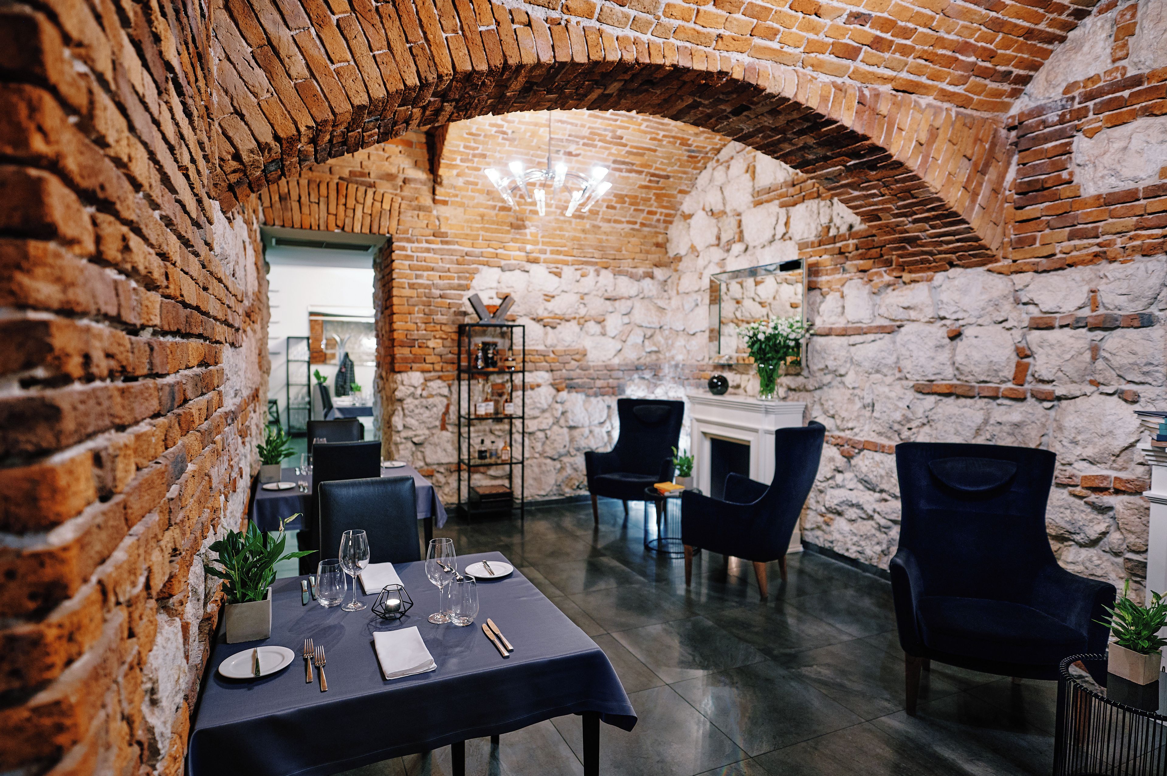 A dining area with brick walls, a stone fireplace, and modern furniture.