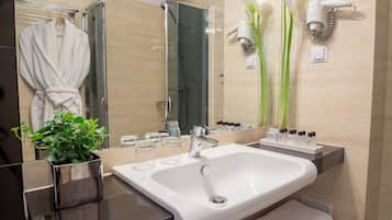 Une salle de bain moderne avec une douche à l’italienne en verre, un lavabo blanc et un miroir.