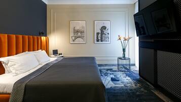 Een moderne hotelkamer met een groot bed, een televisie en twee ingelijste foto's aan de muur.