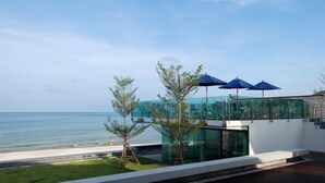 A modern building with a glass facade overlooking a beach. - Samui Resotel Beach Resort (Koh Samui)