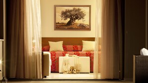 A hotel room with a bed, a painting of a tree, and a pool in the foreground.