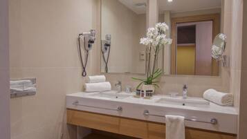 A modern bathroom with a wooden vanity, two sinks, a large mirror, and a toilet.