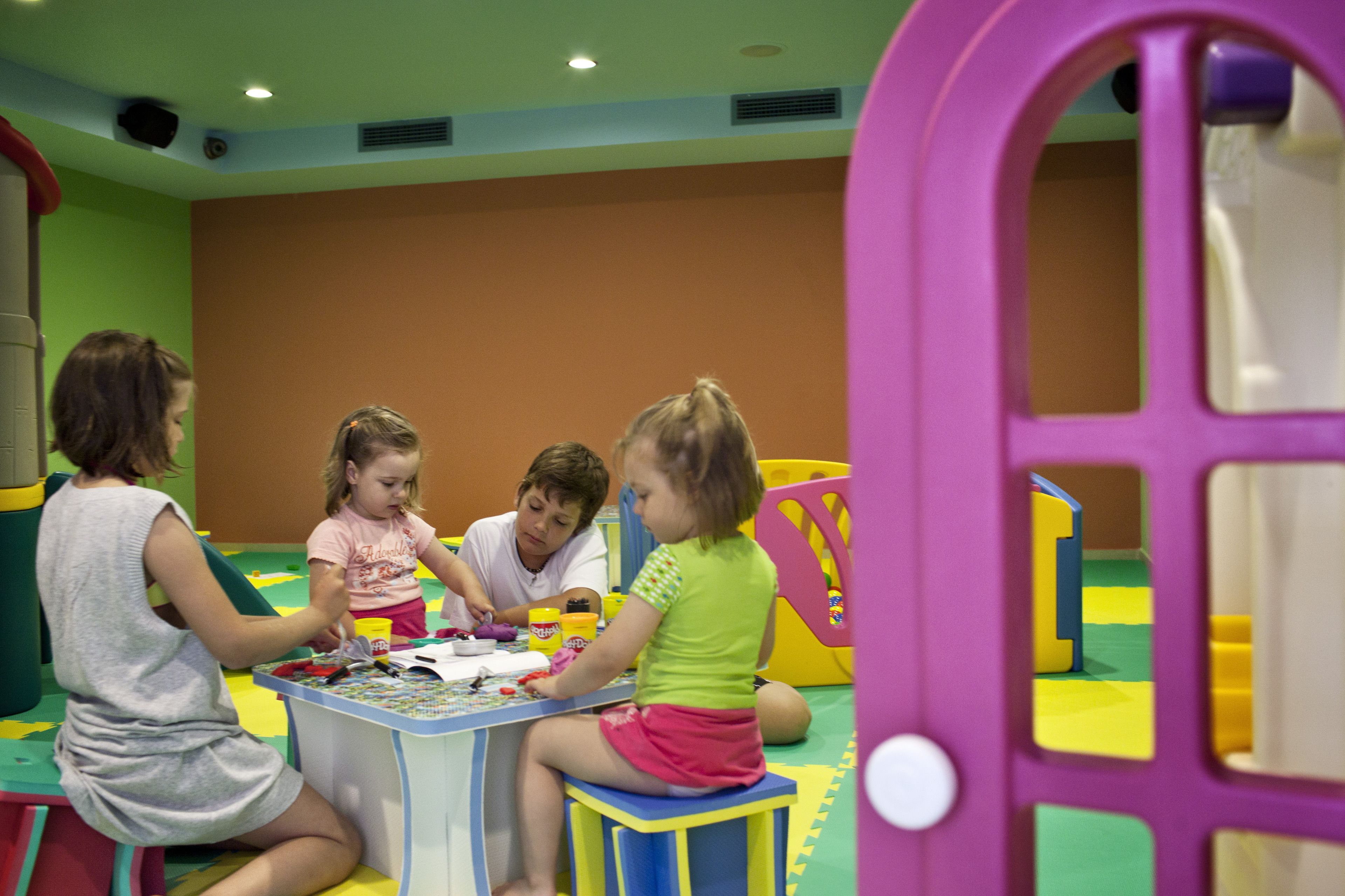 Un groupe d’enfants joue à une table dans un espace de jeux intérieur aux couleurs vives.