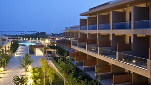 A modern hotel with multiple balconies, a swimming pool, and a landscaped garden area.