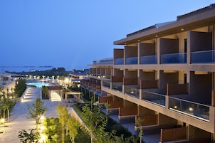 Un hotel moderno con varios balcones, piscina y un jardín paisajístico.