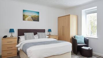 Un dormitorio con cama, dos mesitas de noche, un armario, una ventana y un cuadro en la pared.