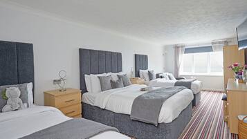 A hotel room with two beds, a wooden dresser, a TV, and a window with curtains.
