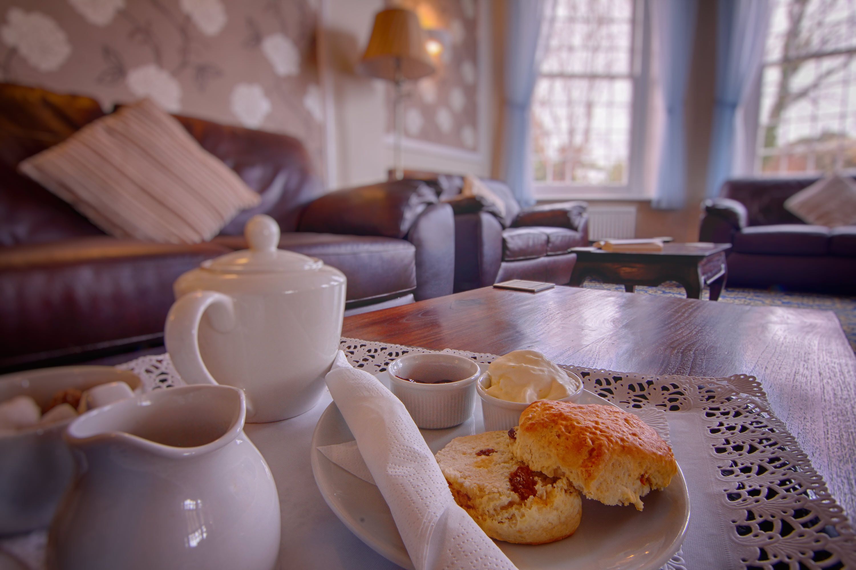 A cozy living room with a coffee table set for tea, a sofa, and a decorative wall.