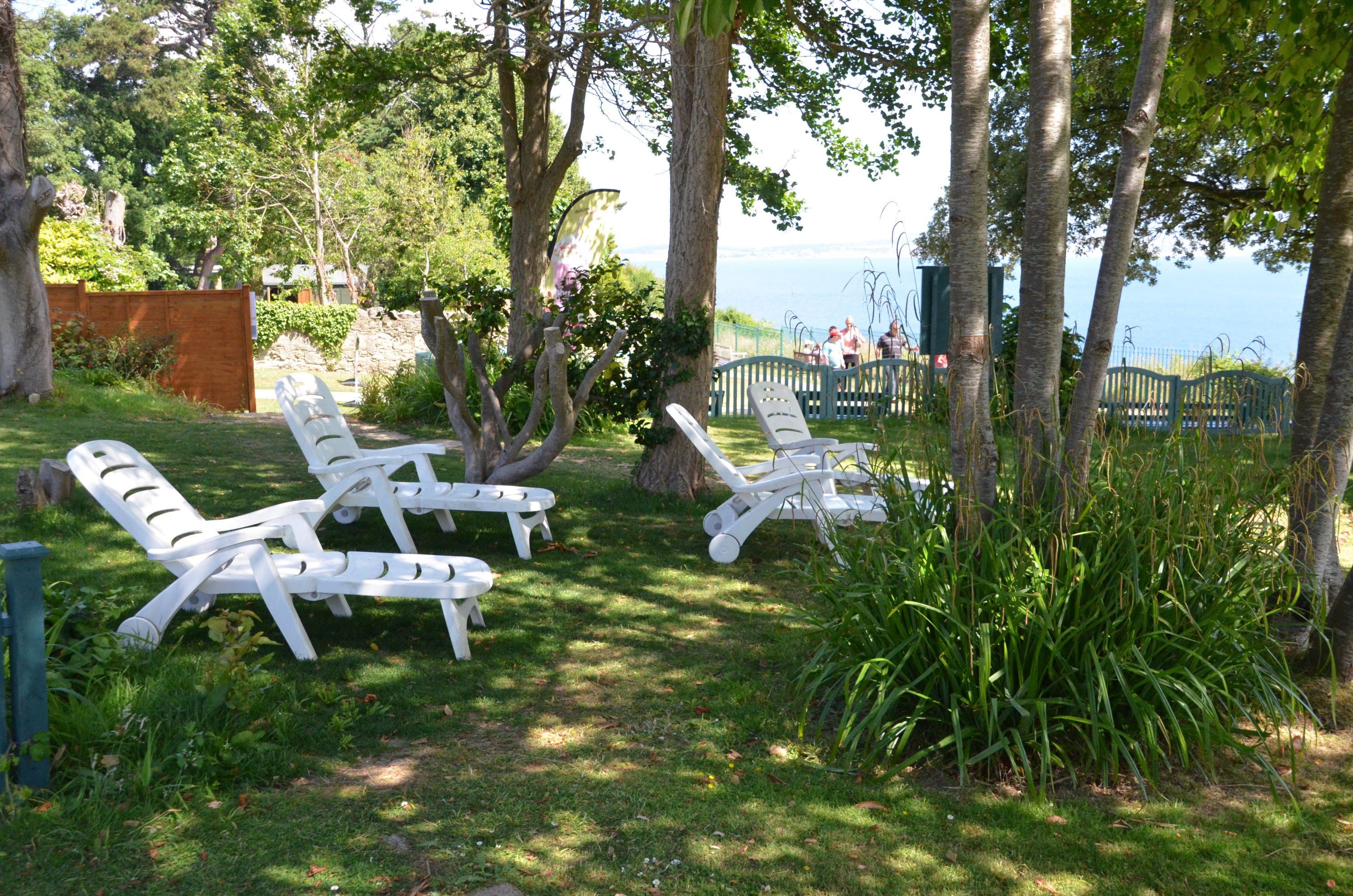 A serene outdoor seating area with white lounge chairs and a view of the sea.