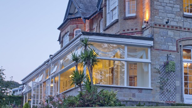A historic building with large windows and a balcony, featuring a stone facade and a moon in the sky. - Luccombe Manor Country House Hotel (Shanklin)