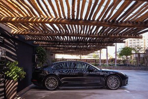 A black car parked under a wooden pergola structure.