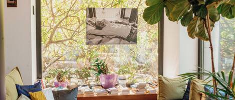 A cozy reading nook with a window seat, books, and potted plants.