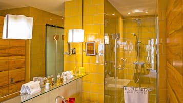 A modern bathroom with a glass shower enclosure, a large mirror, and a glass-topped vanity.